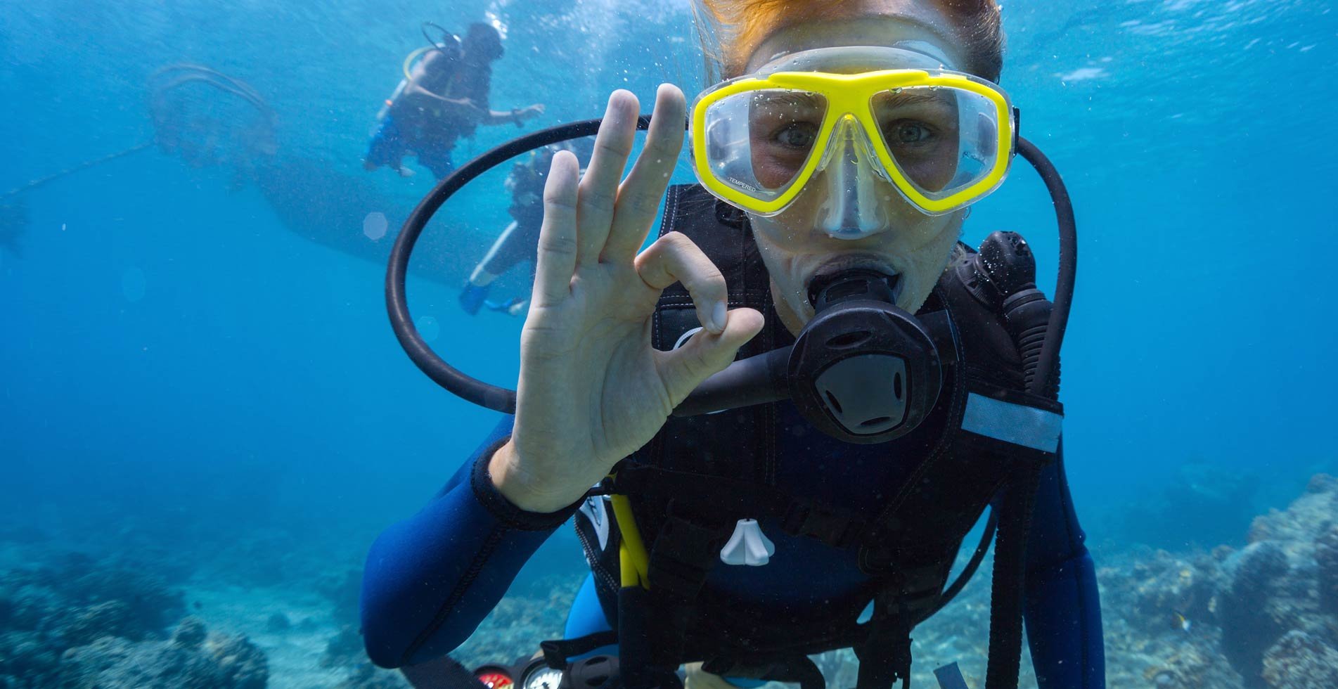 Taucherin mit OK-Zeichen am Riff